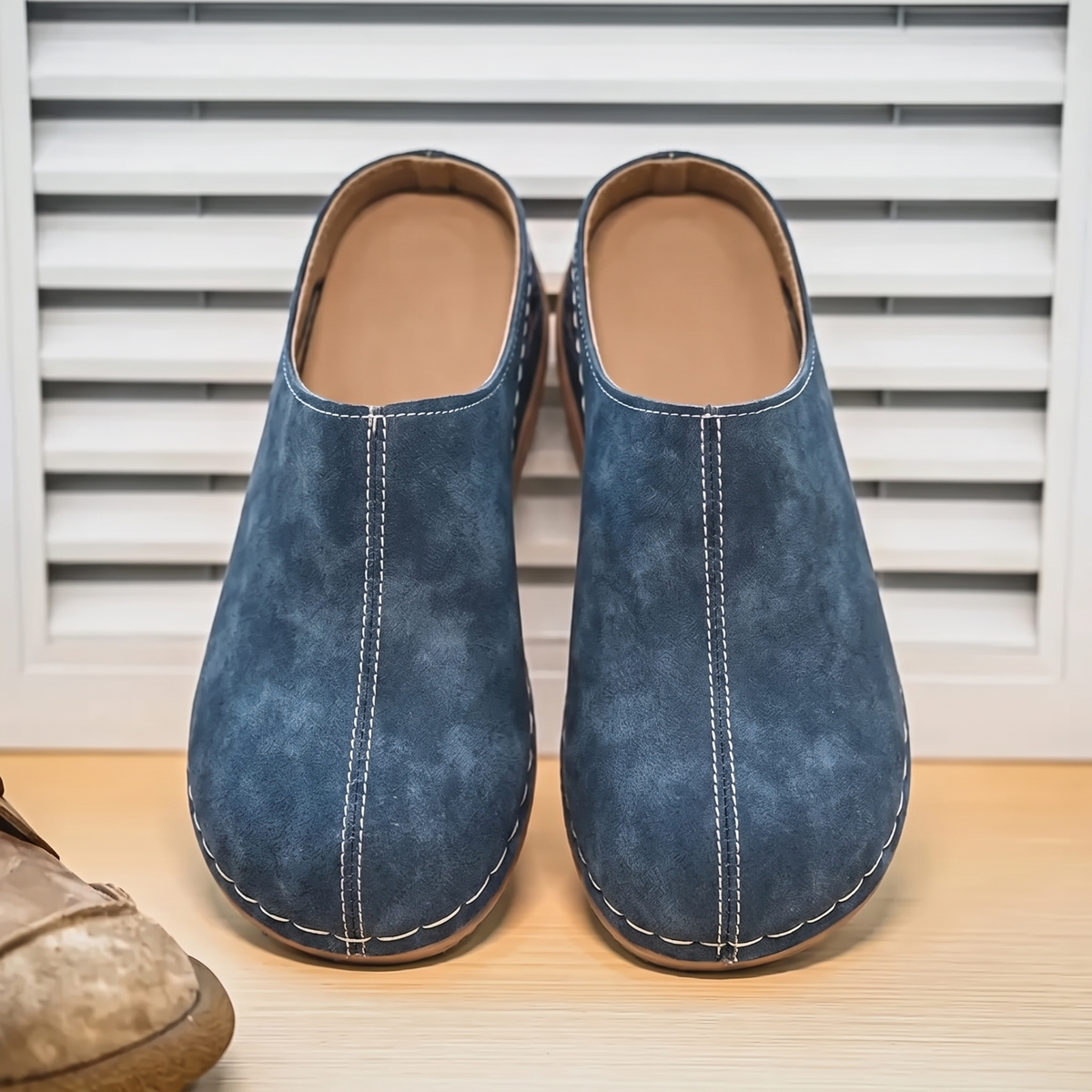 Zapatillas Ortopédicas sobre fondo de persiana blanca